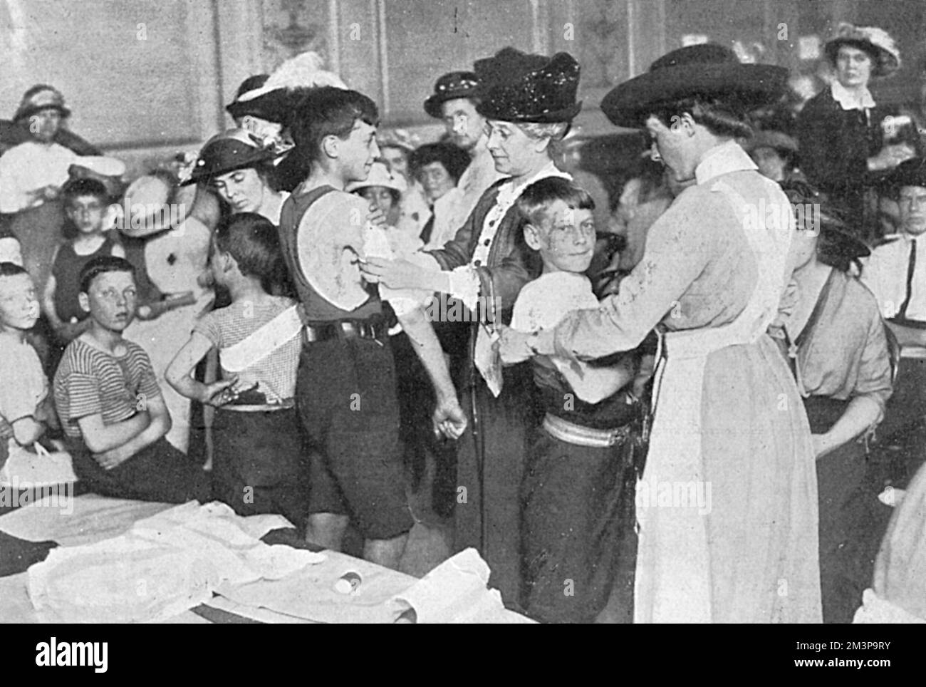 Infermieri volontari che praticano le loro tecniche di bendaggio sui bambini al Kensington Town Hall poco dopo lo scoppio della prima guerra mondiale. Data: 1914 Foto Stock