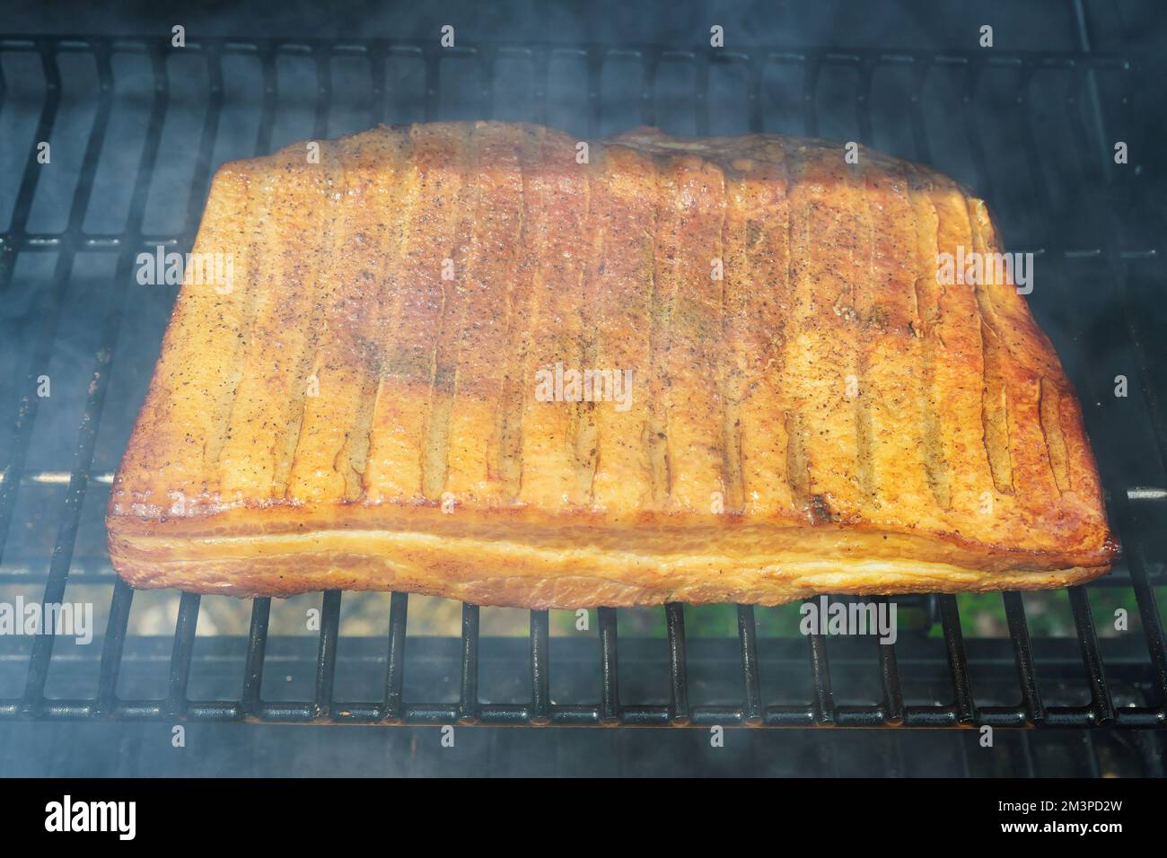 Alla griglia barbecue tradizionale arrosto di pancetta affumicata intera fatta in casa è alla griglia alla perfezione Foto Stock