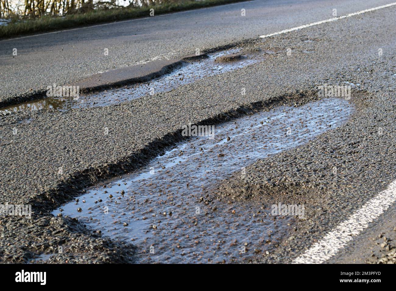 Buche pericolose in una strada pubblica o autostrada. Mancanza di manutenzione. Mancanza di finanziamenti attraverso l’austerità. Foto Stock