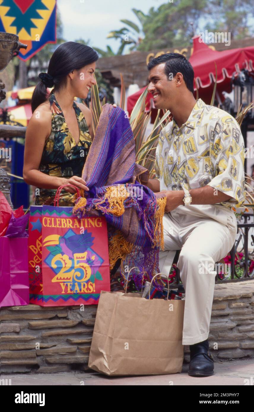 Giovane coppia ispanica fuori shopping, pausa per guardare alcune delle cose che hanno comprato. Foto Stock