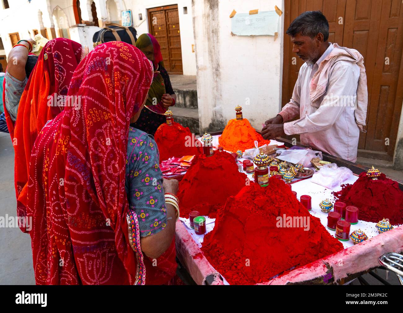 Uomo indiano che vende le polveri colorate rosse alle donne, Rajasthan, Pushkar, India Foto Stock