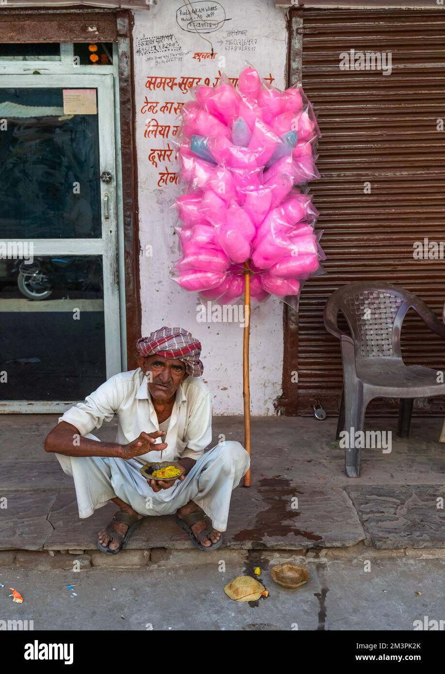 Rajasthani uomo mangiare per strada e vendere dolci rosa, Rajasthan, Pushkar, India Foto Stock