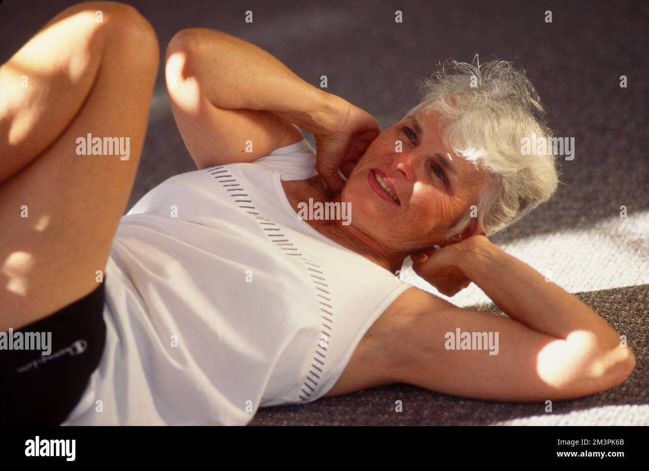 Donna più anziana che si posa sulla schiena facendo esercizi Foto Stock