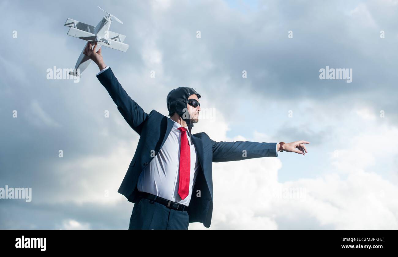 persona d'affari in tuta e cappello pilota lancio aereo giocattolo su sfondo cielo Foto Stock