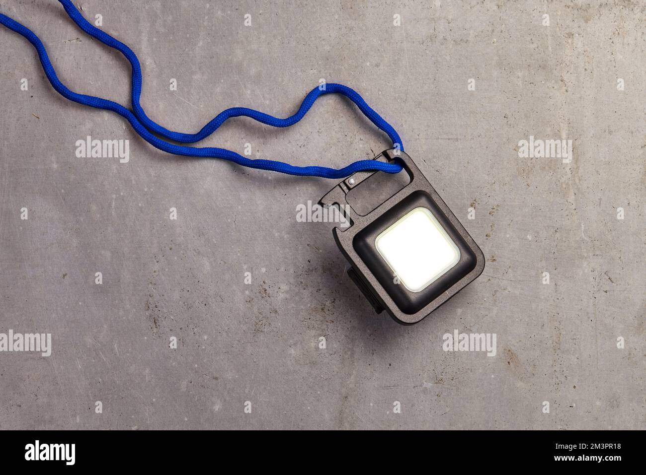 una mini luce portachiavi con una stringa blu che funziona per l'illuminazione di emergenza Foto Stock