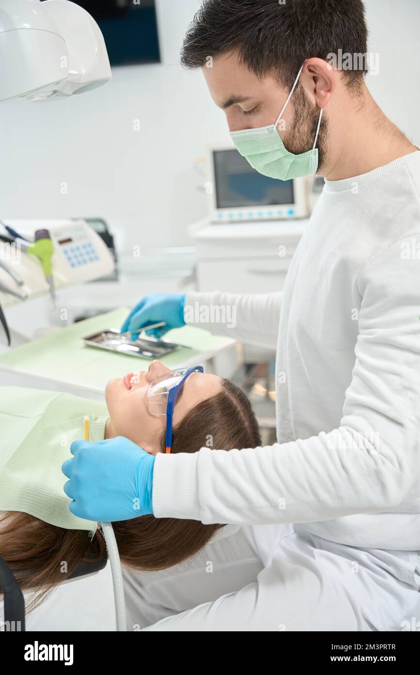 Dentista professionista che si prepara ad esaminare i denti della donna Foto Stock