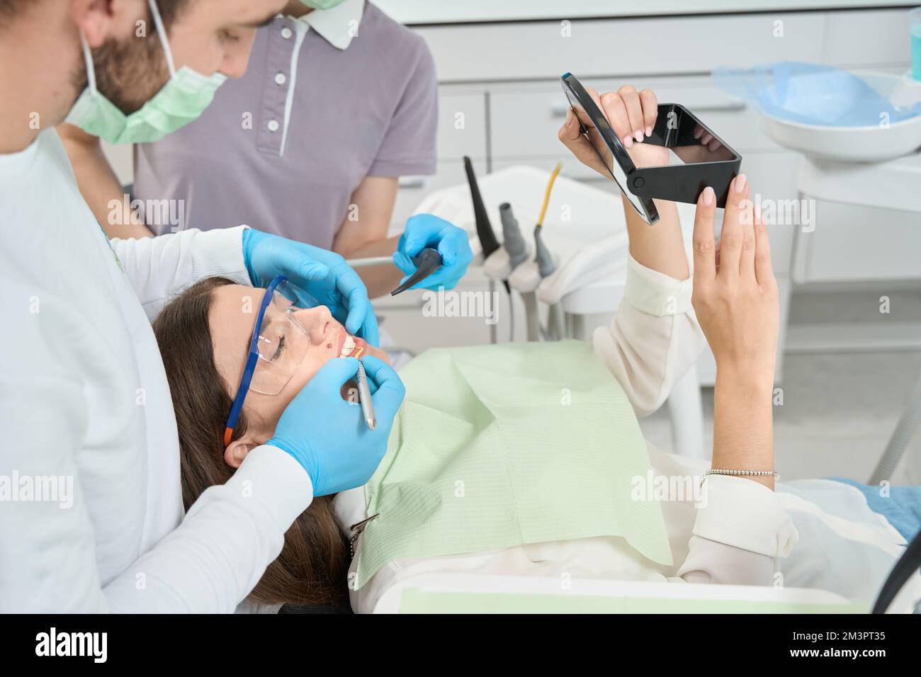 Dentista che conduce la pulizia interdentale sulla giovane donna Foto Stock