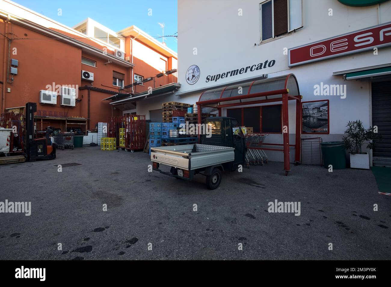 Piazza di fronte ad un negozio con un Ape Piaggio parcheggiato Foto Stock