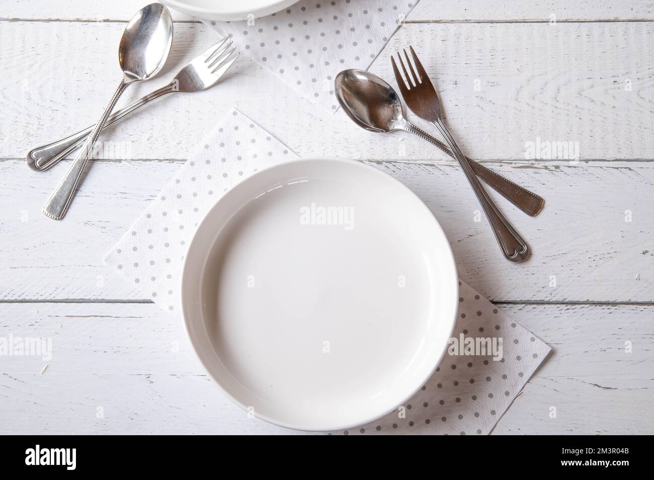 Piatto bianco vuoto con forchetta e cucchiaio su fondo bianco Foto Stock