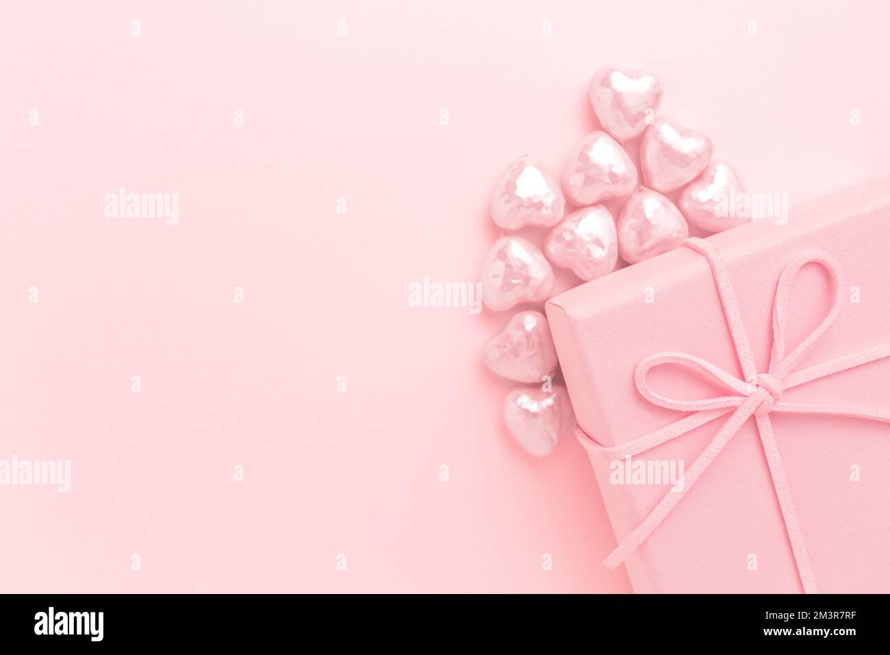 Scatola regalo rosa con cuori piccoli su sfondo rosa. Foto Stock