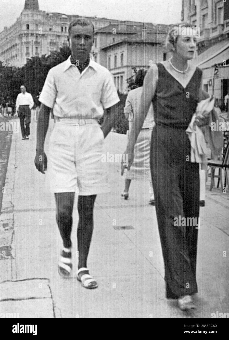 Un uomo che indossa una polo bianca, bottoni-up, pantaloncini bianchi e sandali bianchi, mostrando chiaramente l'influenza del tennis sulla moda - un tipico vestito indossato sulla Costa Azzurra durante gli anni '1930s. Data: 1934 Foto Stock