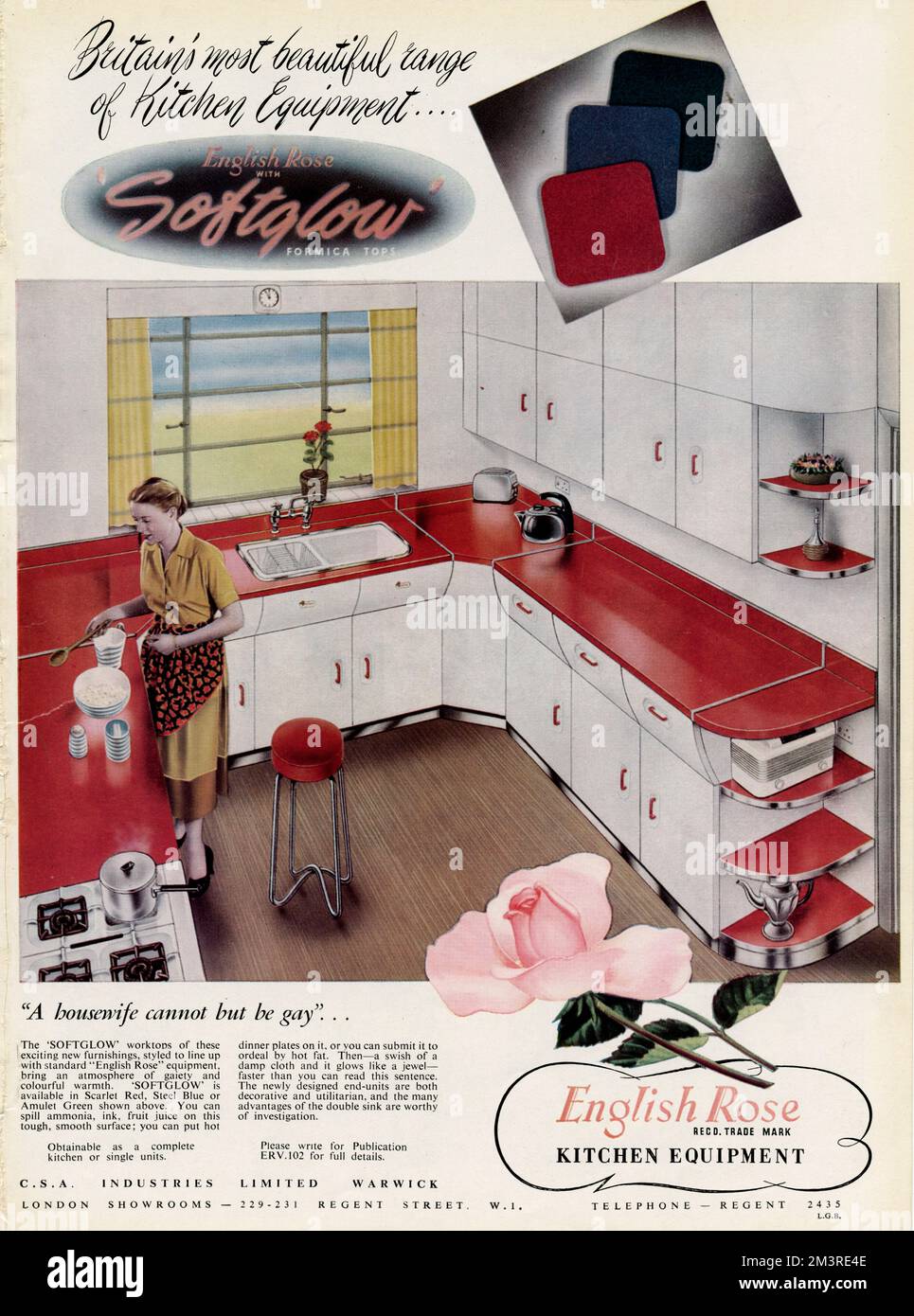 Giovane casalinga che cucina nella sua nuova cucina attrezzata 'English Rose'. Disponibile con un'ampia scelta di colori del piano di lavoro softglow, rosso scarlatto, blu acciaio e verde amuleto. 1952 Foto Stock