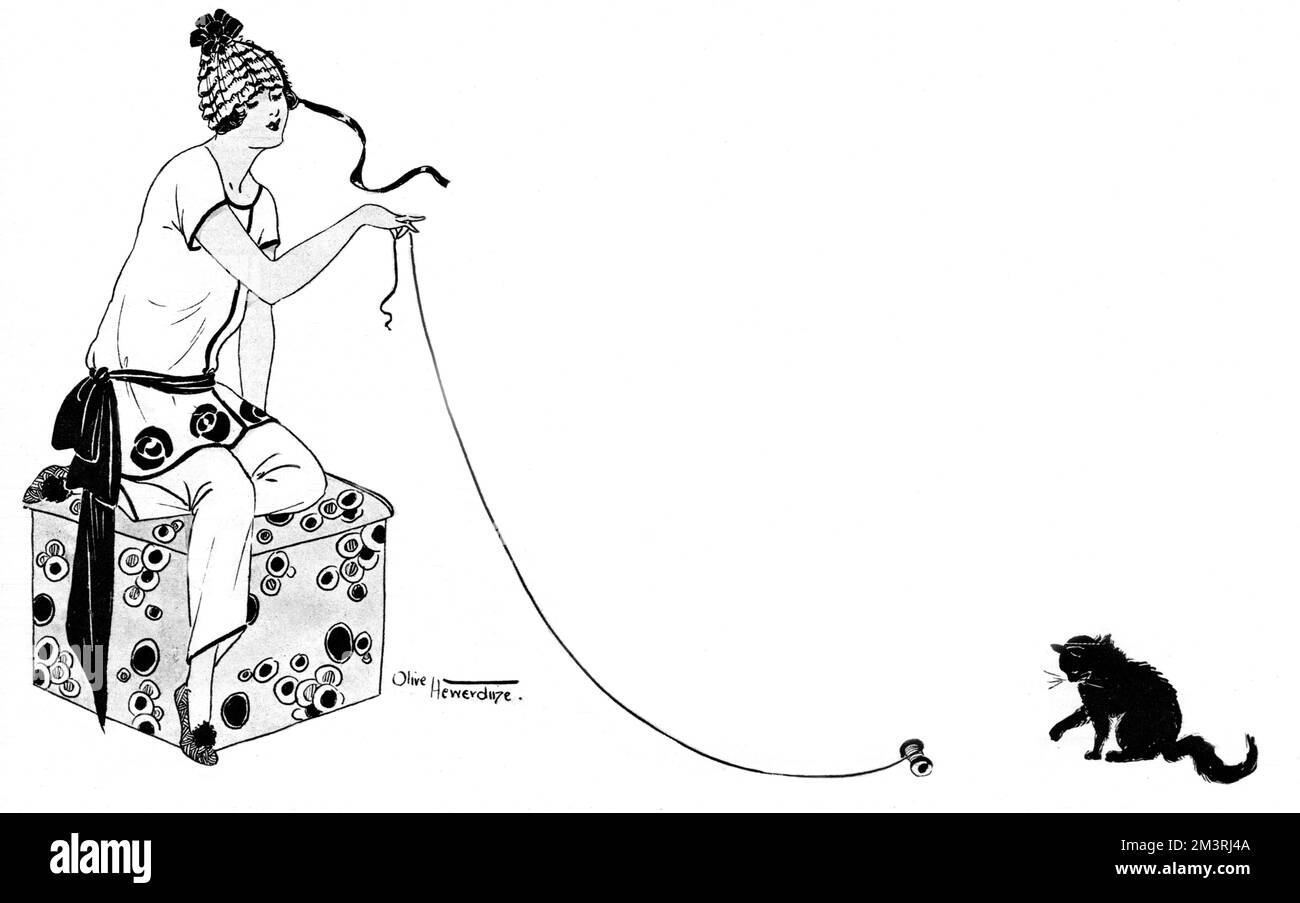 Una giovane donna elegante che indossa un set di Marshall &amp; pigiami di Snelgrove in crepe-de-chine bianca (con motivi floreali ricamati neri), giocando con il suo cucciolo nero con un rotolo di cotone e filo. Data: 1923 Foto Stock