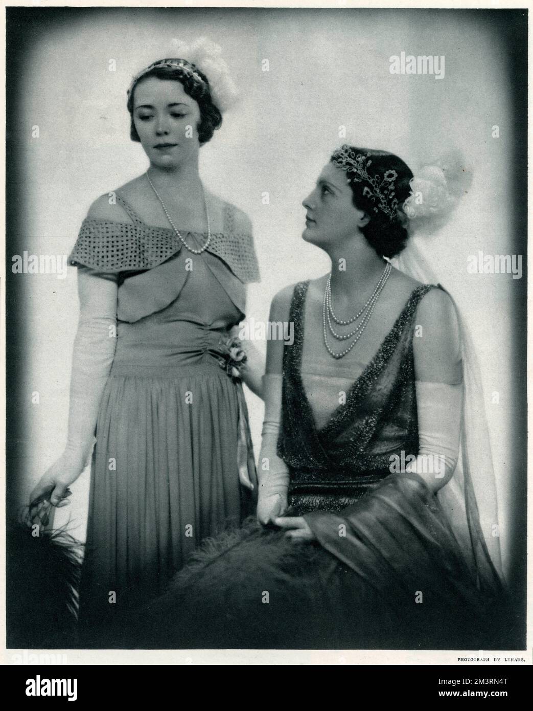 Entrambi i debutantes indossando bei abiti di Russell e Allen per May Court. (A sinistra) il raso verde foglia è scelto per la rana del debutante, il treno e il corpo alto-gesso essendo adornato con un trellis formato di rouleaux di satin. (A destra) migliaia di perline d'acciaio sul vestito di rete di seta inglese grigio fine si sono stabiliti alla perfezione. Il ricamo a mano dà peso alla gonna sottile, le cui linee non sono obsurate dal treno di rete. Data: 1933 Foto Stock
