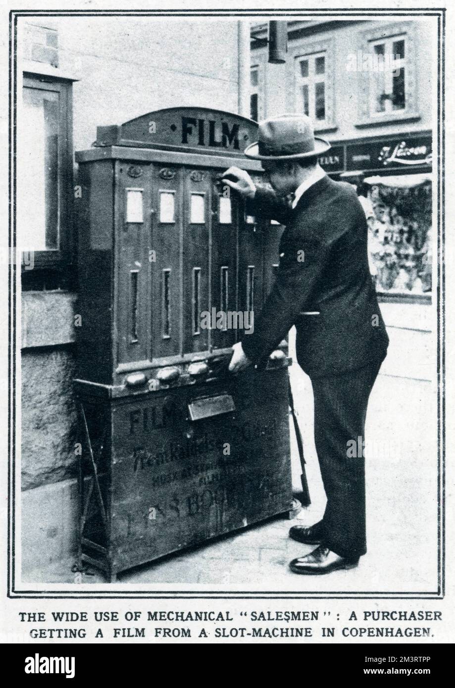 L'ampio uso di 'salesmen' meccanici: Un acquirente che ottiene un film da una slot-machine a Copenaghen, questo è stato utilizzato al di fuori di un negozio di commercianti per mantenere la vendita dei loro prodotti quando il negozio è stato chiuso. Foto Stock
