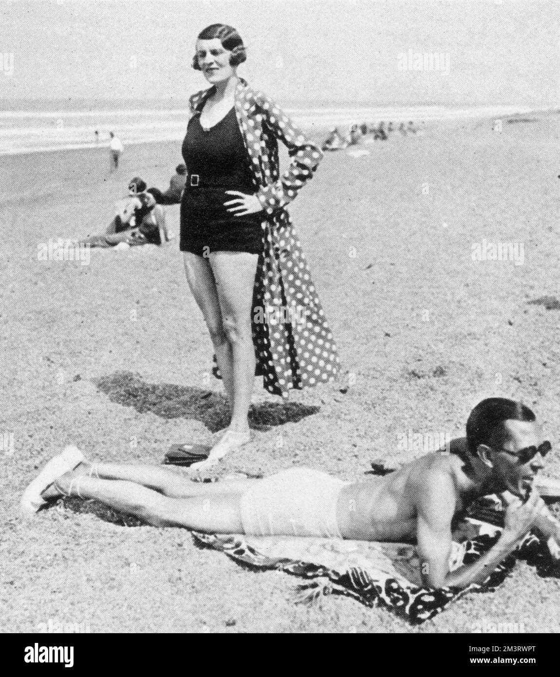 Madame Paul Dubonnet, ex signora Jean Nash, ha regolarmente dichiarato la donna più vestita d'Europa, sulla spiaggia di Biarritz, mentre suo marito, della dinastia delle bevande, si prende il sole nelle vicinanze. 1932 Foto Stock