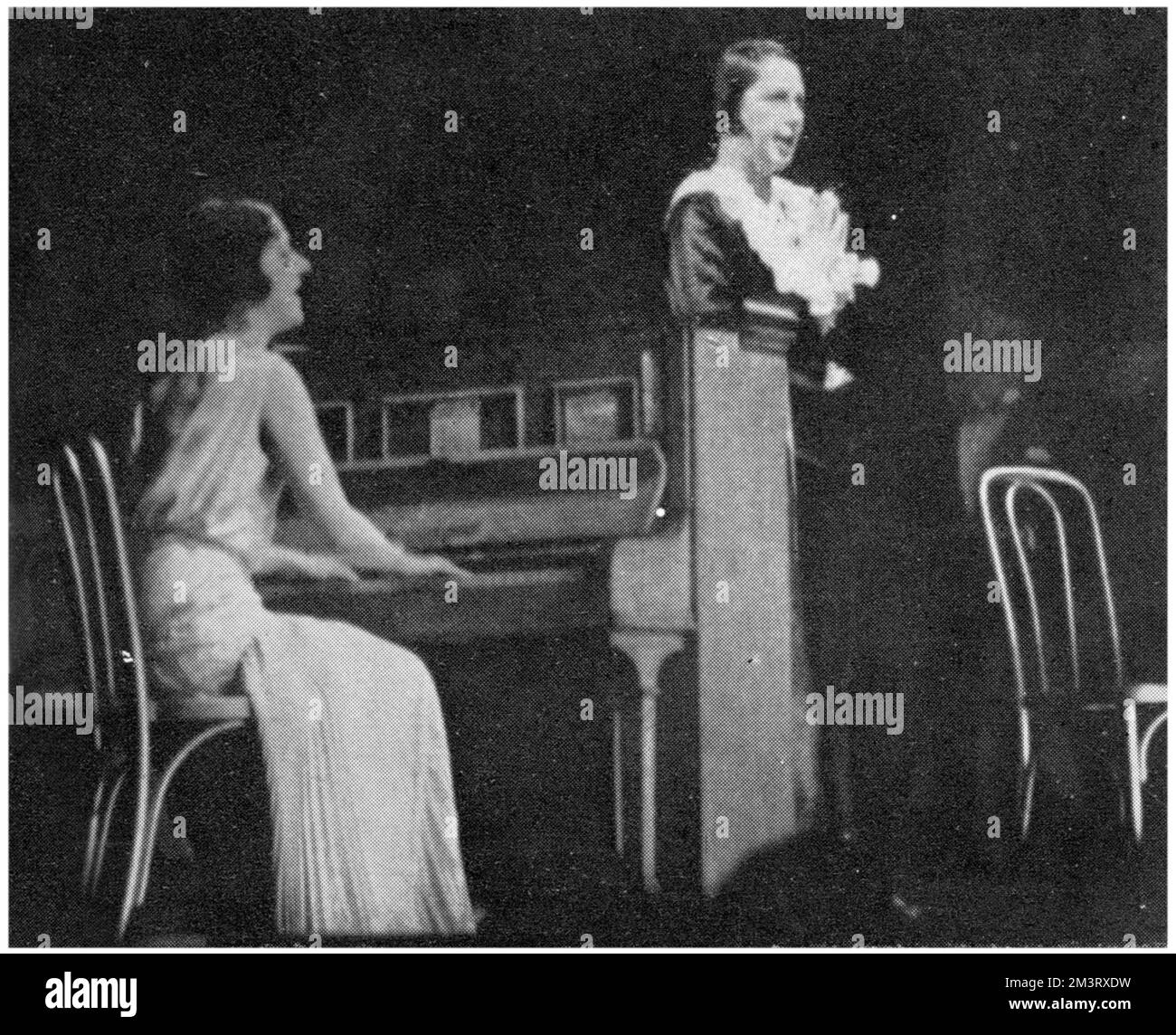 Norah Blaney (a sinistra al pianoforte) e Gwen Farrar in novel revue 'Wonder Bar' al Savoy Theatre. La scena è un nightclub viennese il cui pubblico trabocca dal proprio palcoscenico alle bancarelle e ai cocktail bar. Data: 1930 Foto Stock
