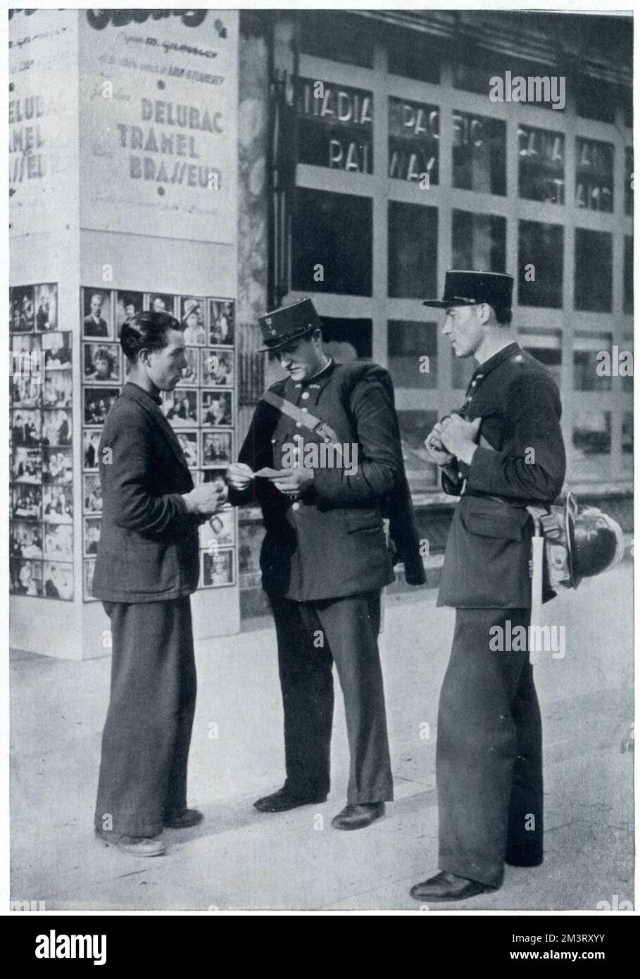 L'uomo sospettato di essere straniero presenta i suoi documenti di identità a due poliziotti paramilitari per l'ispezione a Parigi, poco dopo lo scoppio della guerra. Data: 1939 Foto Stock