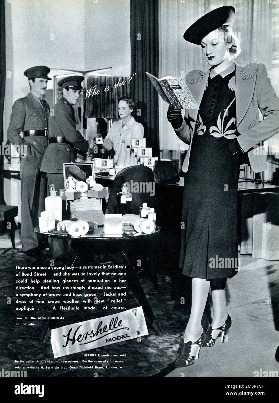 La pubblicità per l'abbigliamento delle donne di Hershelle che mostra una donna in Yardley's di Bond Street apparentemente così inghiottita nel catalogo del negozio, non riesce a realizzare il suo abito favoloso e l'aura magnetica sta attirando l'attenzione di alcuni bei salti in uniforme. 1940 Foto Stock