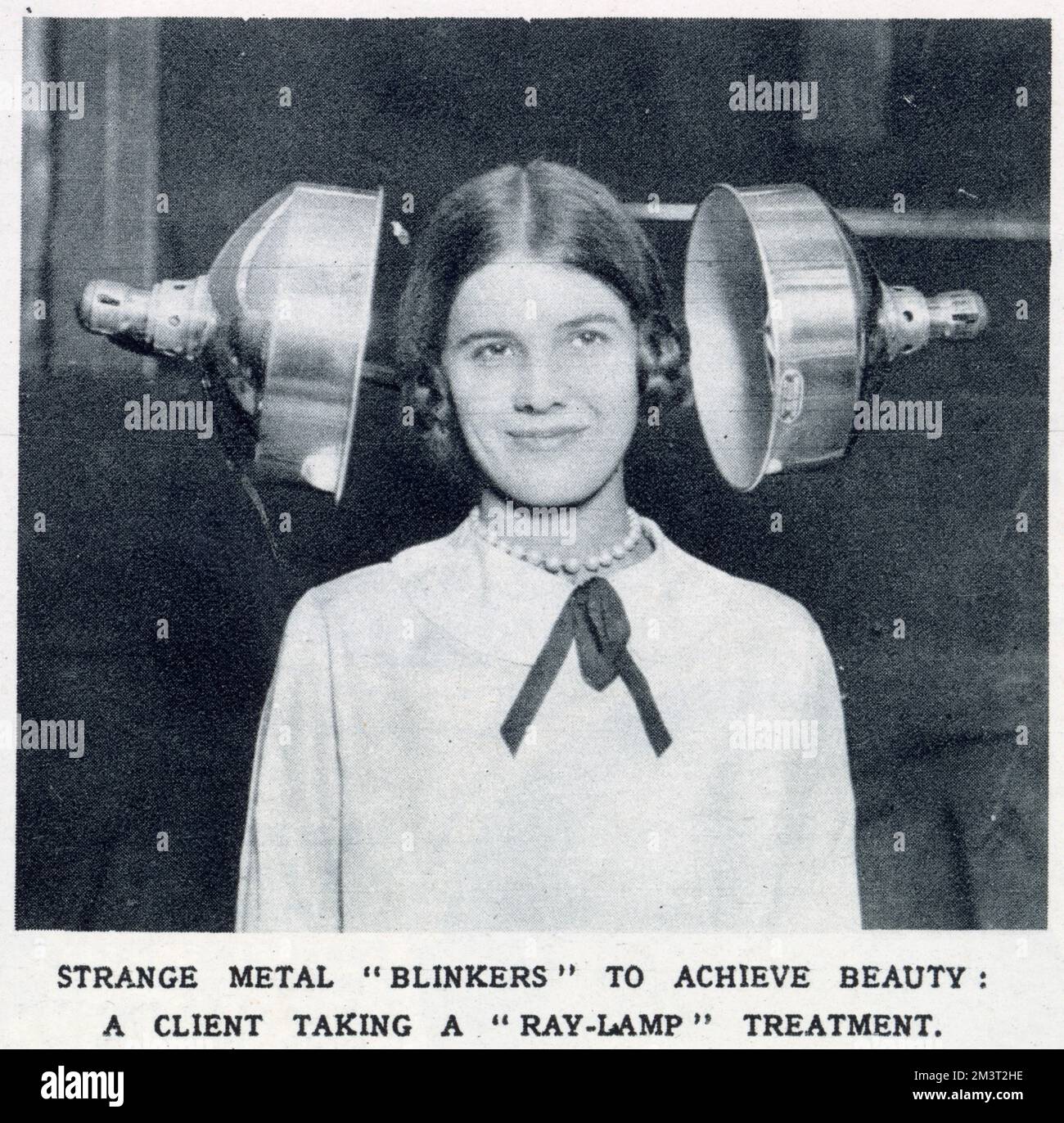 Strange Metal 'Blinkers' per raggiungere la bellezza: Un cliente che prende un trattamento 'Ray-Lamp', esposto alla Fiera annuale dei parrucchieri. Data: 1928 Foto Stock
