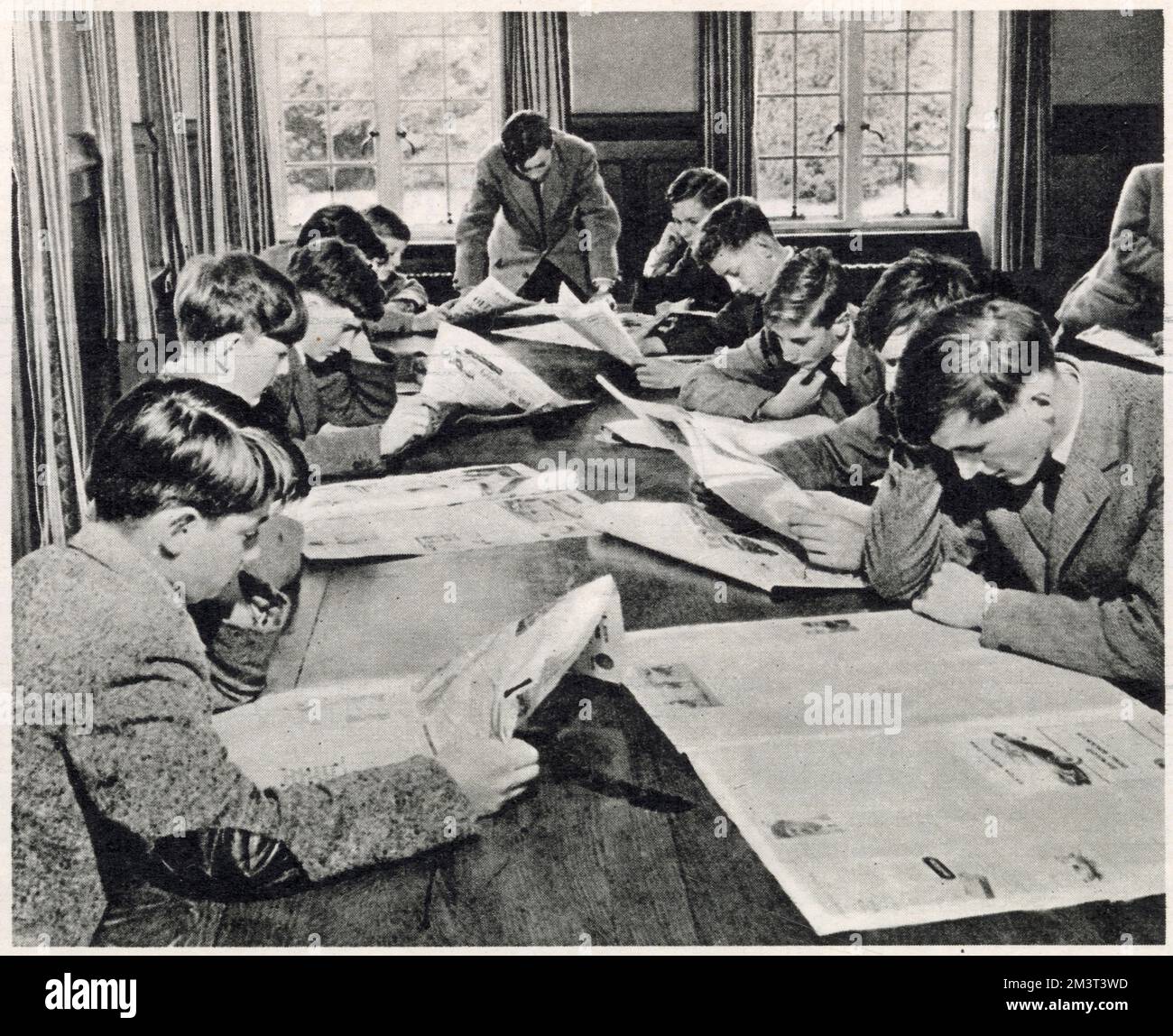 Gli studenti del Wellington College si tengono in contatto con gli eventi in corso, studiando giornali nella sala lettura della scuola. Foto Stock