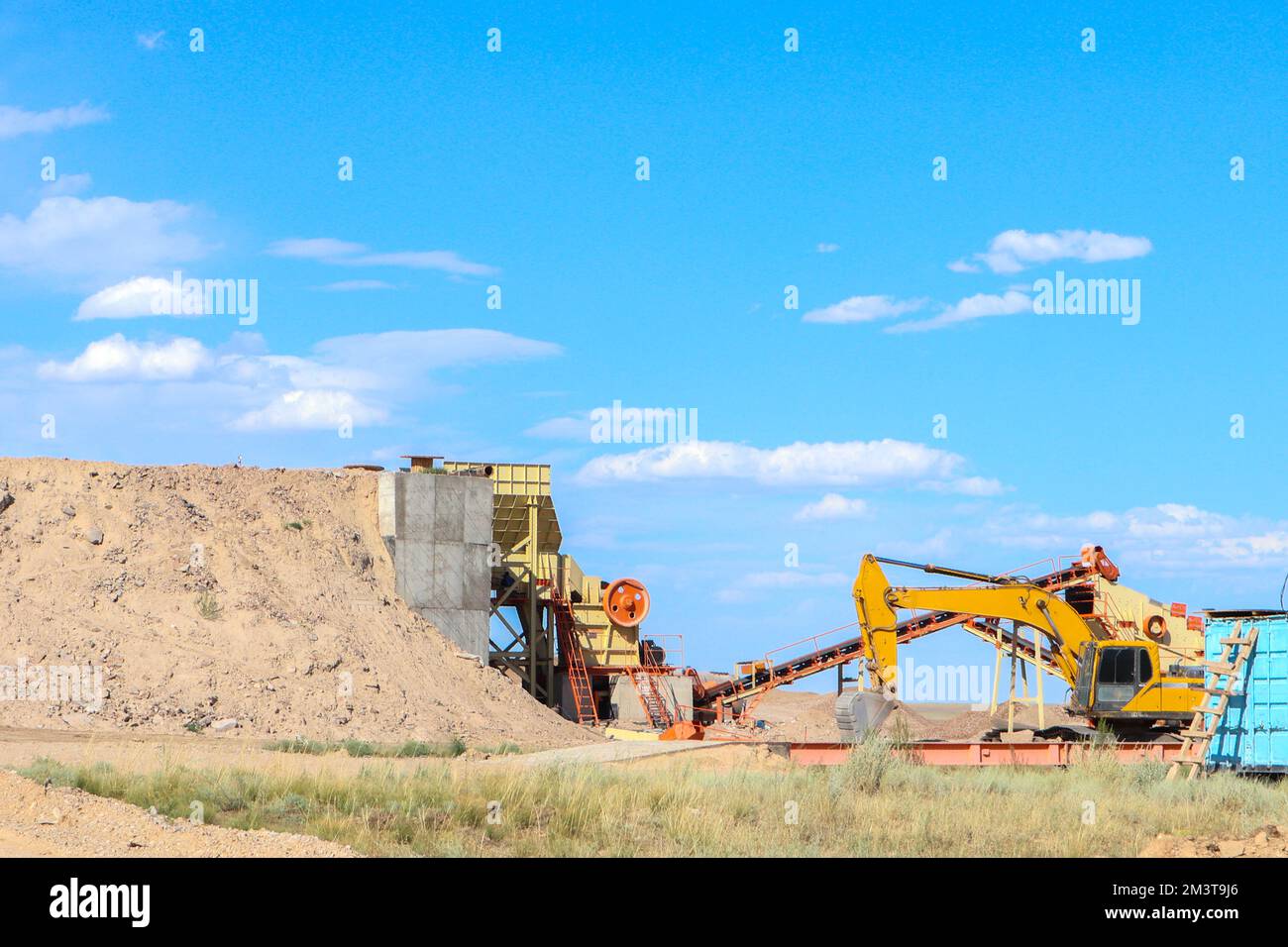 sviluppo di una cava di sabbia. il lavoro dell'escavatore giallo Foto Stock