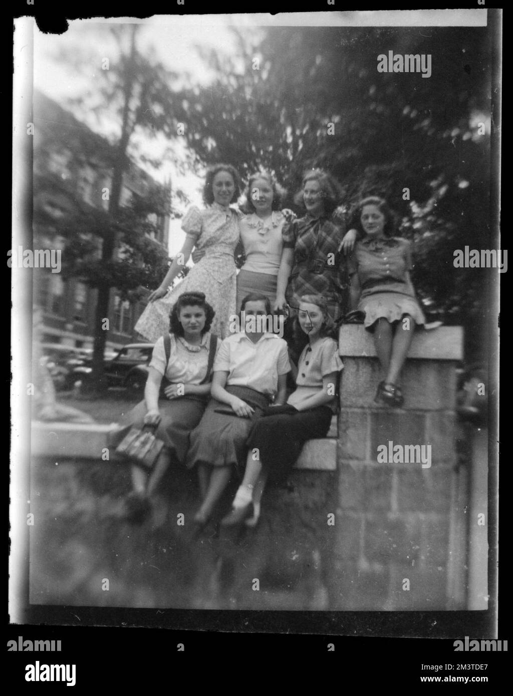 Sette donne posano su un muro di pietra, muri di pietra. Collezione Jack Miller Foto Stock