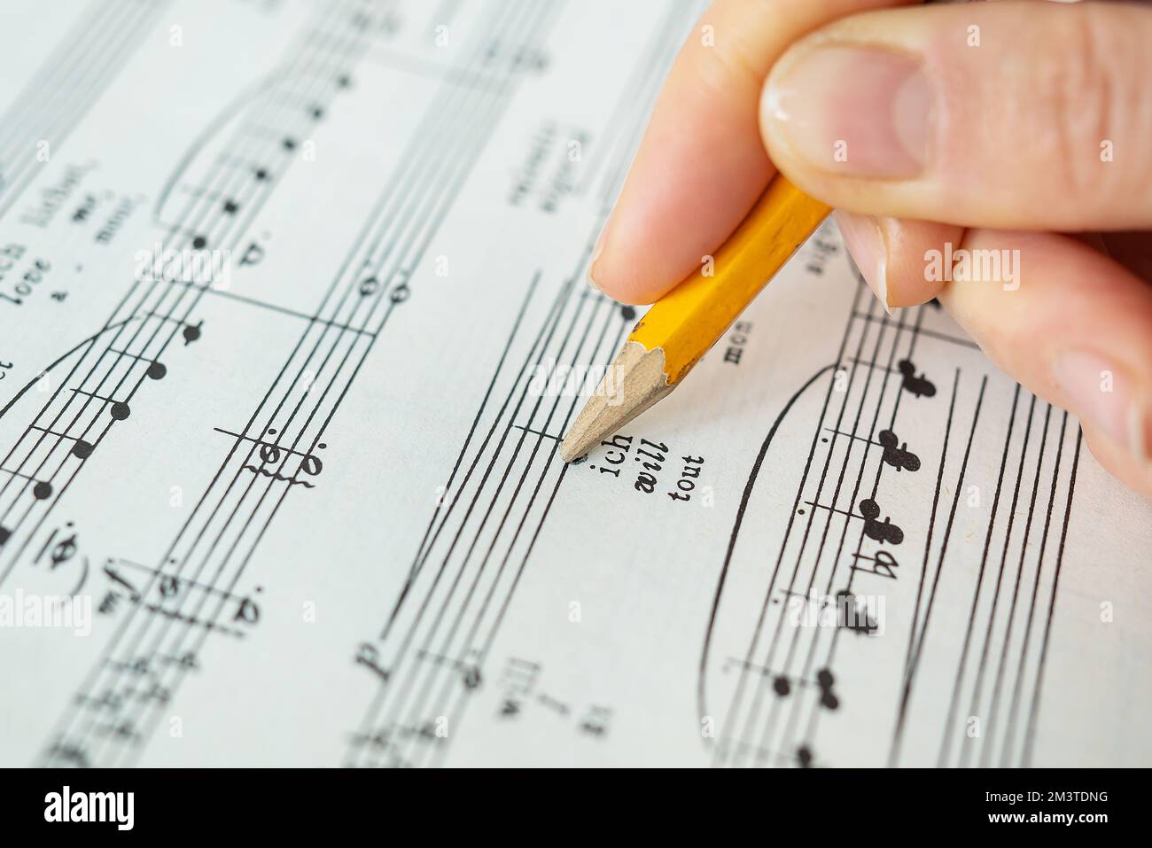 Lviv, Ucraina - 13 dicembre 2022: Partitura per pianoforte, note musicali su carta. La mano prende appunti con una matita su carta. Vista dall'alto Foto Stock