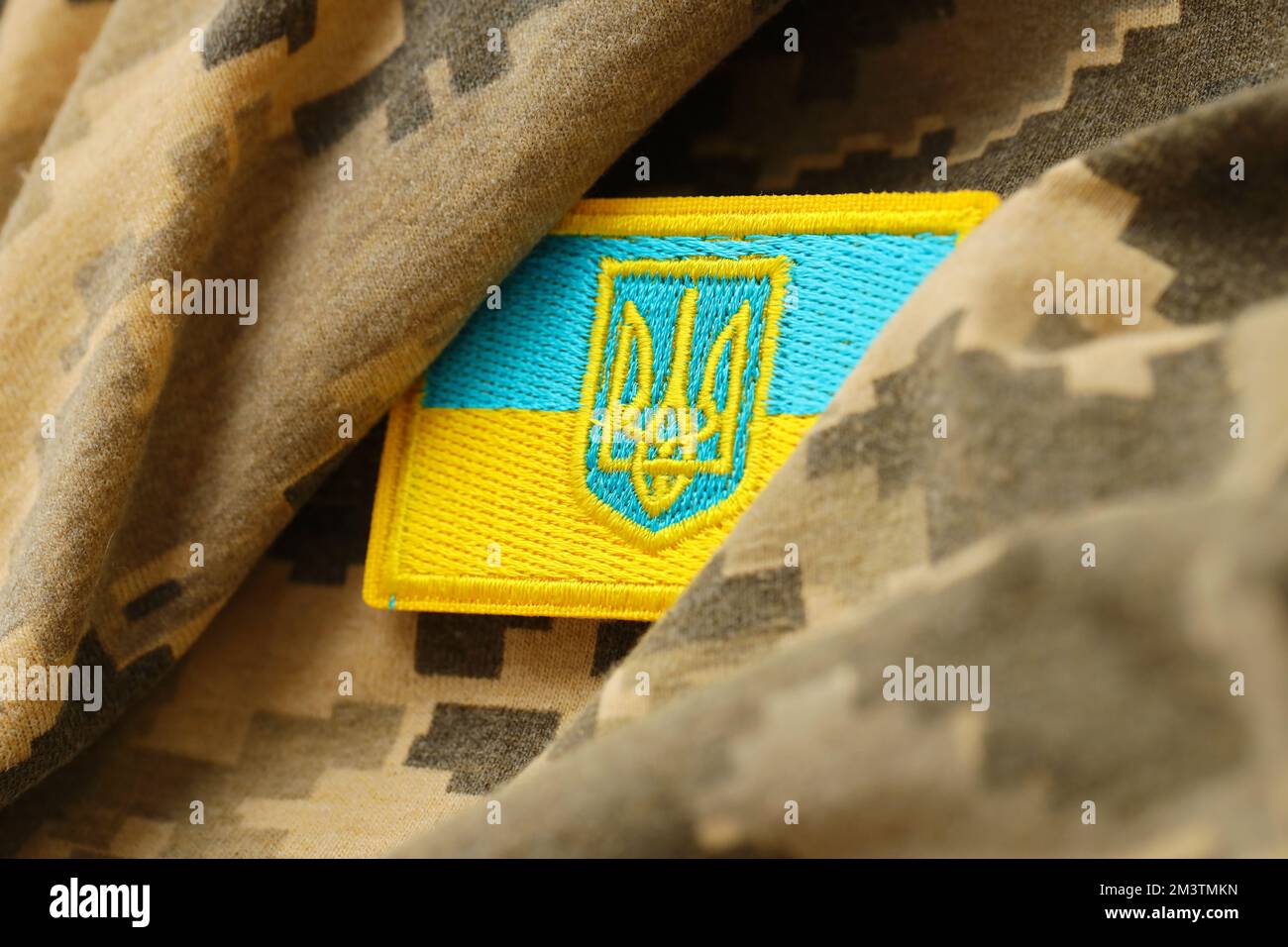 Tessuto camouflage militare digitale Pixeled con bandiera ucraina e stemma a chevron nei colori blu e giallo. Attributi di uniforme soldato ucraino Foto Stock