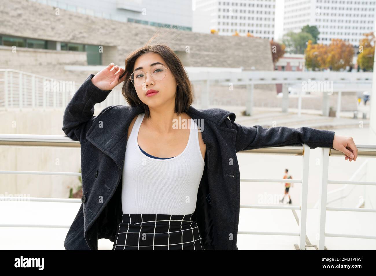 Giovane donna che si affaccia su Railing Downtown Plaza Foto Stock