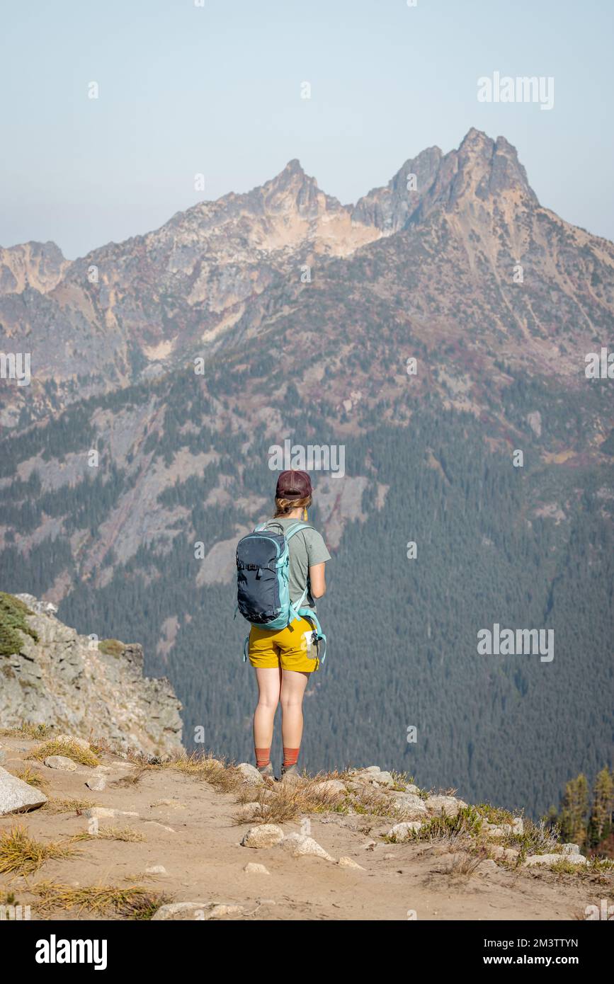 Non identificabile backpacking trekking donna in piedi fuori sul bordo di montagna che domina il terreno sotto, da dove è appena venuto. Grande montagna Foto Stock