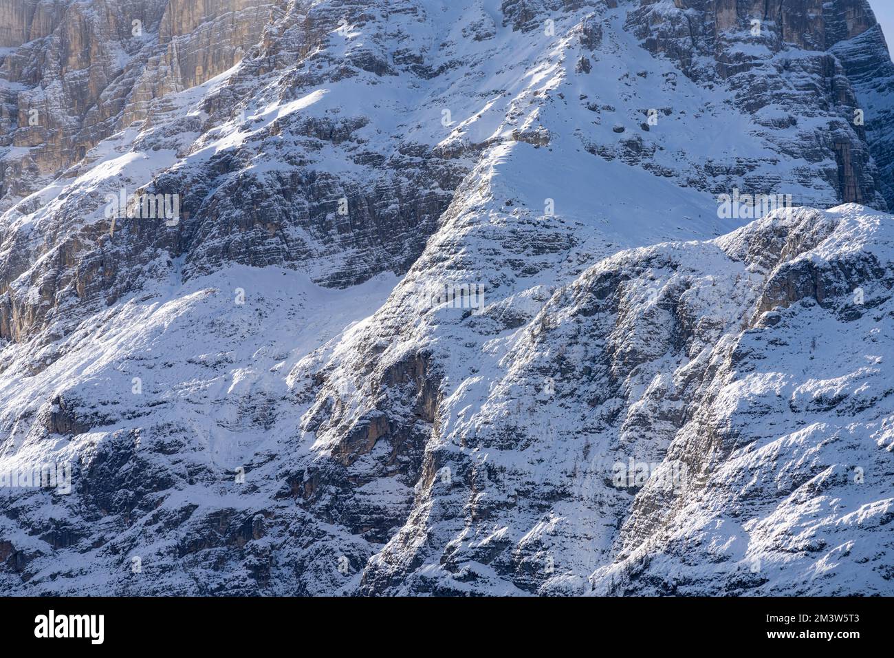 neve e ghiaccio si depositano sulla parete rocciosa di una montagna in inverno Foto Stock