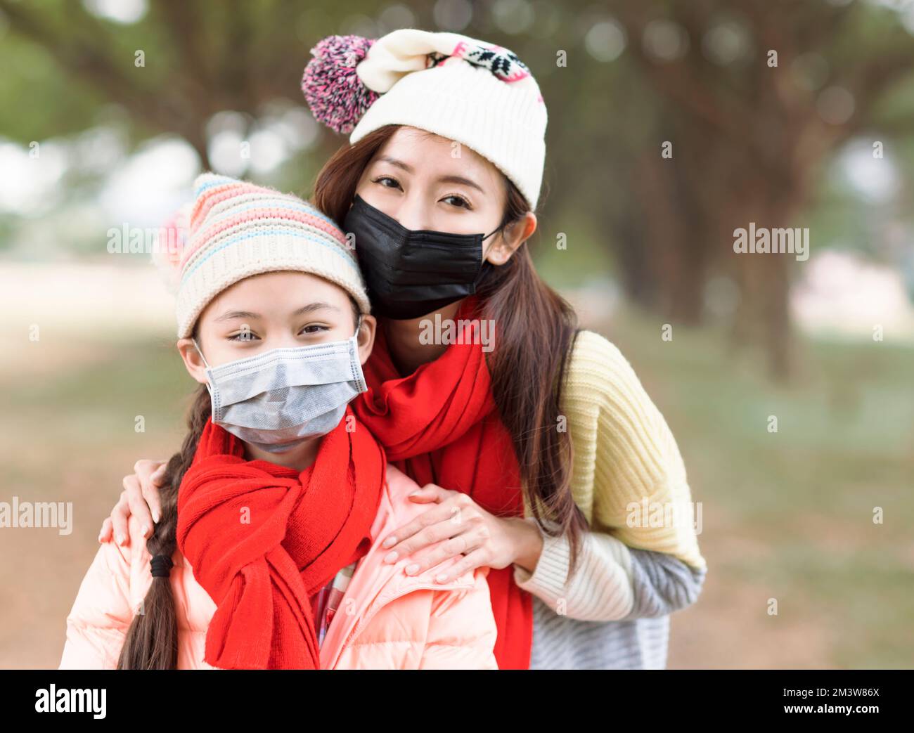 Madre e figlia che indossano una maschera medica protettiva per la protezione dalle malattie da virus Foto Stock