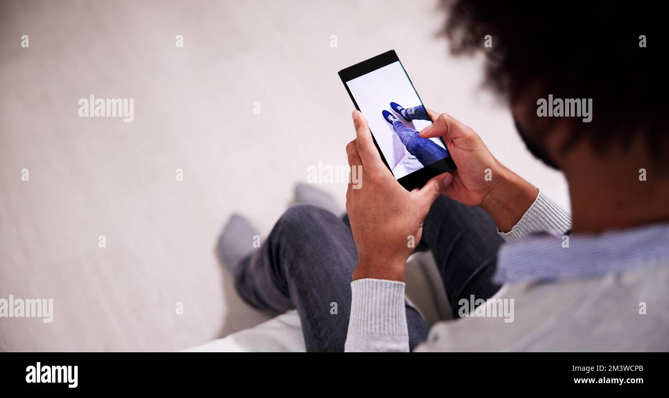 Uomo che prova Virtual Sneakers in negozio o app Store AR Foto Stock
