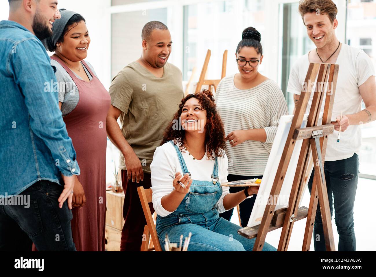 Tutti ci leghiamo attraverso l'essere creativi. una giovane donna attraente seduta e che spiega le sue opere d'arte ai suoi amici durante una lezione d'arte. Foto Stock