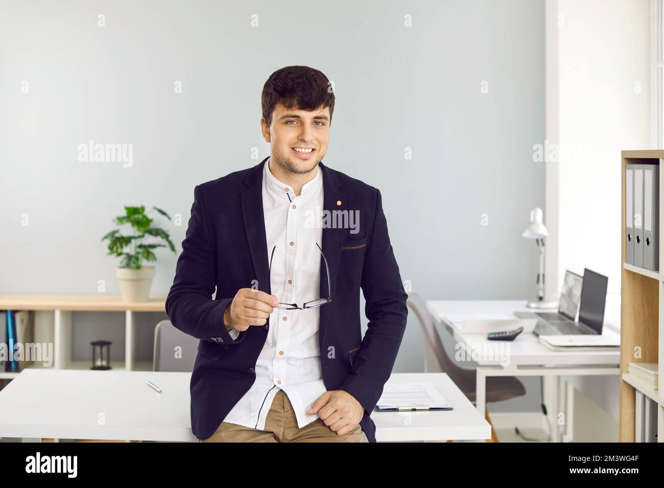 Ritratto di un uomo d'affari giovane, di successo e fiducioso che si pone in ufficio di impresa. Foto Stock