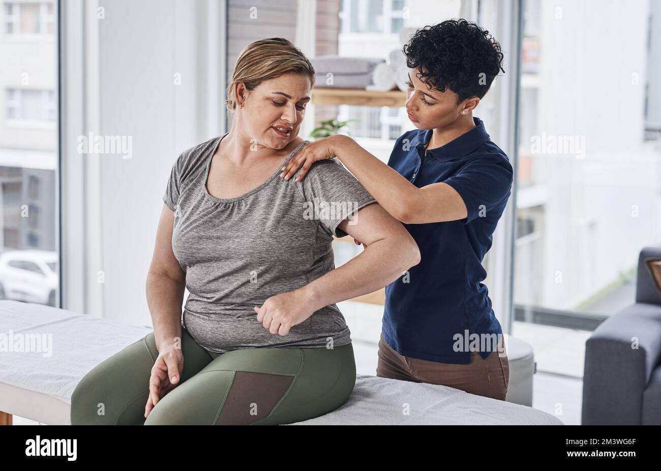 D'ora in poi, è necessario semplificarlo. una giovane fisioterapista che cura una donna matura all'interno del suo ufficio in una clinica. Foto Stock