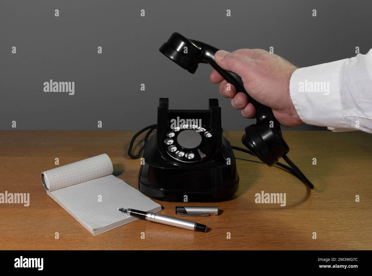 Installazione a posteriori. La mano raggiunge il telefono. Vecchio apparecchio telefonico su un tavolo di legno, spazio copia Foto Stock