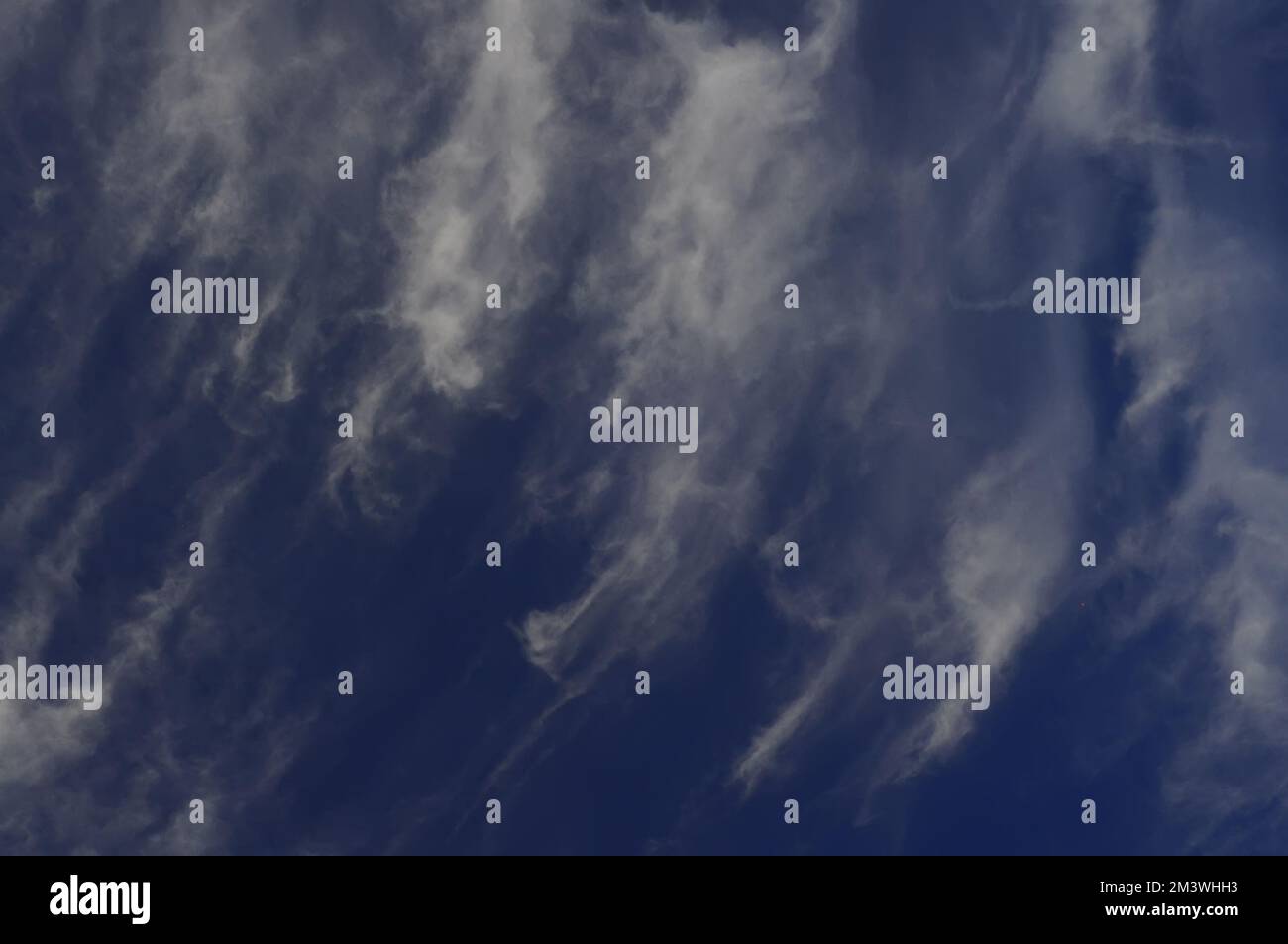 Cielo blu scuro con nuvole di piume strappate, sfondo Foto Stock