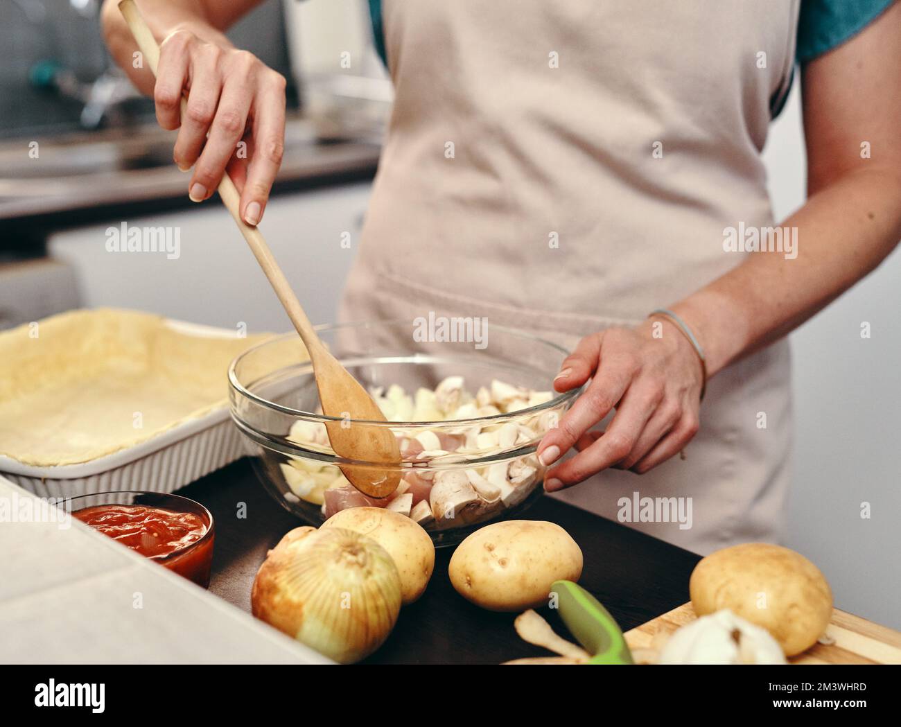 Mescolando in su nella cucina. una donna irriconoscibile che si cuoce in cucina a casa. Foto Stock