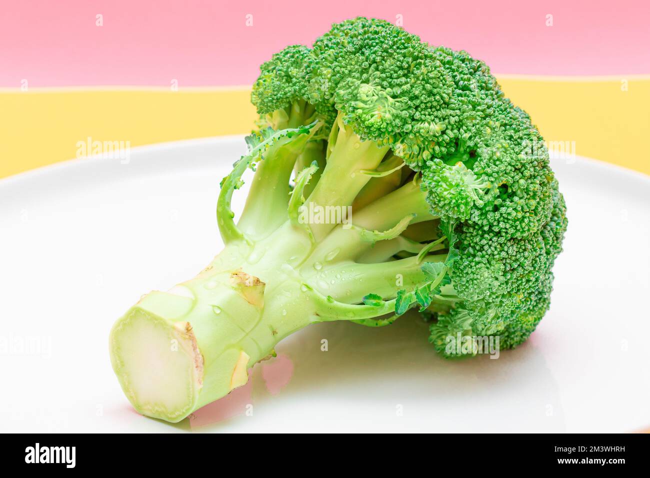 Broccoli freschi e crudi su piatto bianco. Cavolo verde non fatto. Cultura vegana e vegetariana. Cibo crudo. Alimentazione sana e dieta vegetale Foto Stock