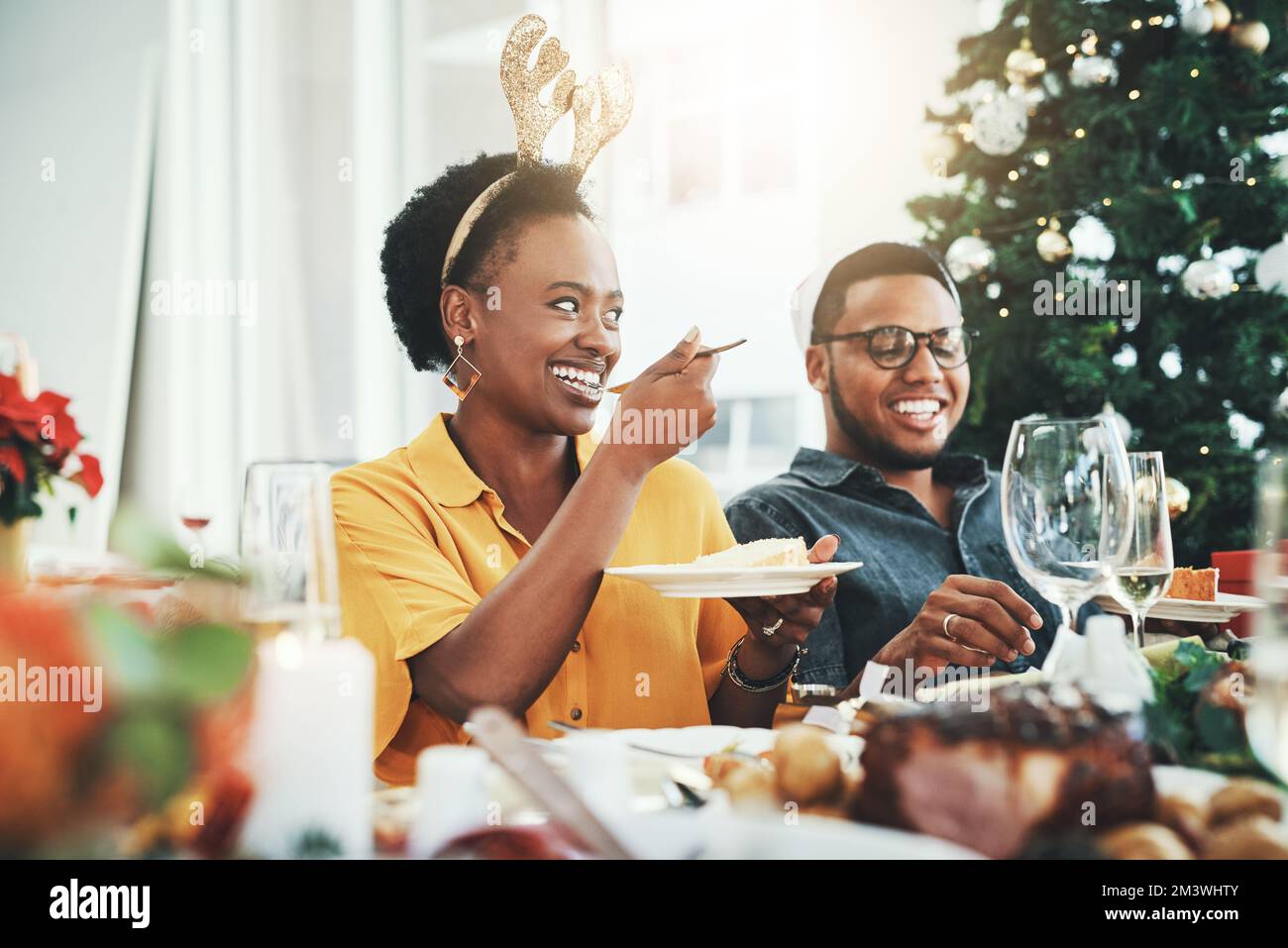Le cose dolci portano sempre un sorriso al suo volto. Una giovane donna attraente che mangia la torta mentre ha pranzo con il suo marito il giorno di Natale nel paese. Foto Stock
