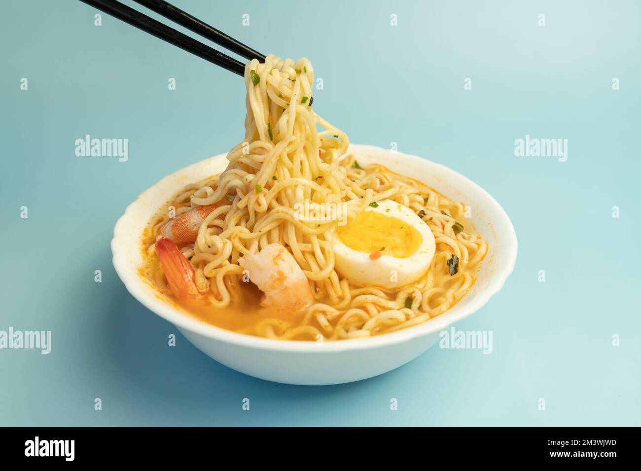 Zuppa di spezie in stile tailandese e spaghetti ricoperti di gamberetti, chiamato Tom Yum Goong su ciotola bianca con bastoncini, a base di gamberetti e peperoncino Mama, caldi Foto Stock