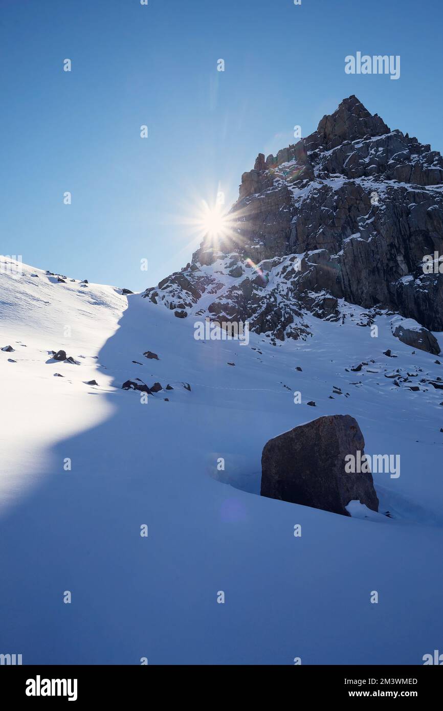 Giorno di sole sulle montagne di alta neve paesaggio con sole bagliore bagliore contro il cielo blu nel periodo invernale in Kazakistan Foto Stock
