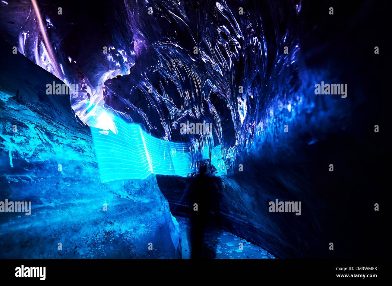 Paesaggio di incredibile grotta di ghiaccio glaciale con luci blu a LED fascio all'interno di una parete di ghiaccio profondo nel ghiacciaio invernale di montagna in Kazakistan Foto Stock