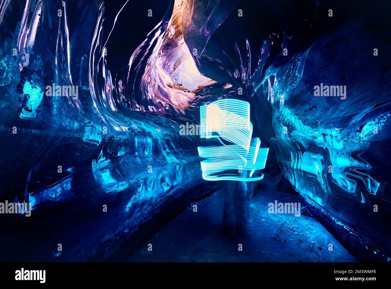 Paesaggio di incredibile grotta di ghiaccio glaciale con luci blu a LED fascio all'interno di una parete di ghiaccio profondo nel ghiacciaio invernale di montagna in Kazakistan Foto Stock