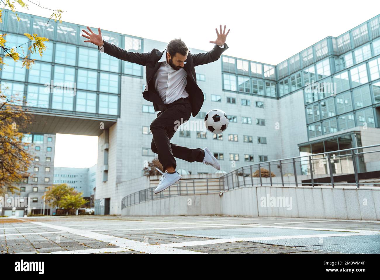 Immagine di un uomo d'affari e di un giocatore di calcio freestyle fare trucchi con la palla per strada. Concetto di sport e uomini d'affari Foto Stock