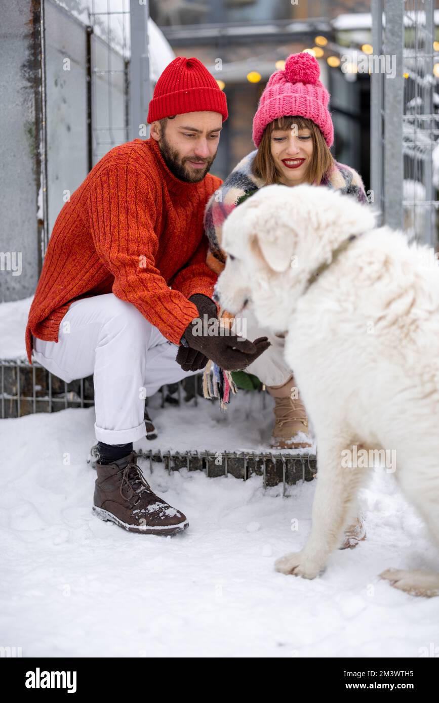 Giovane coppia con cane su un portico della loro casa in inverno Foto Stock