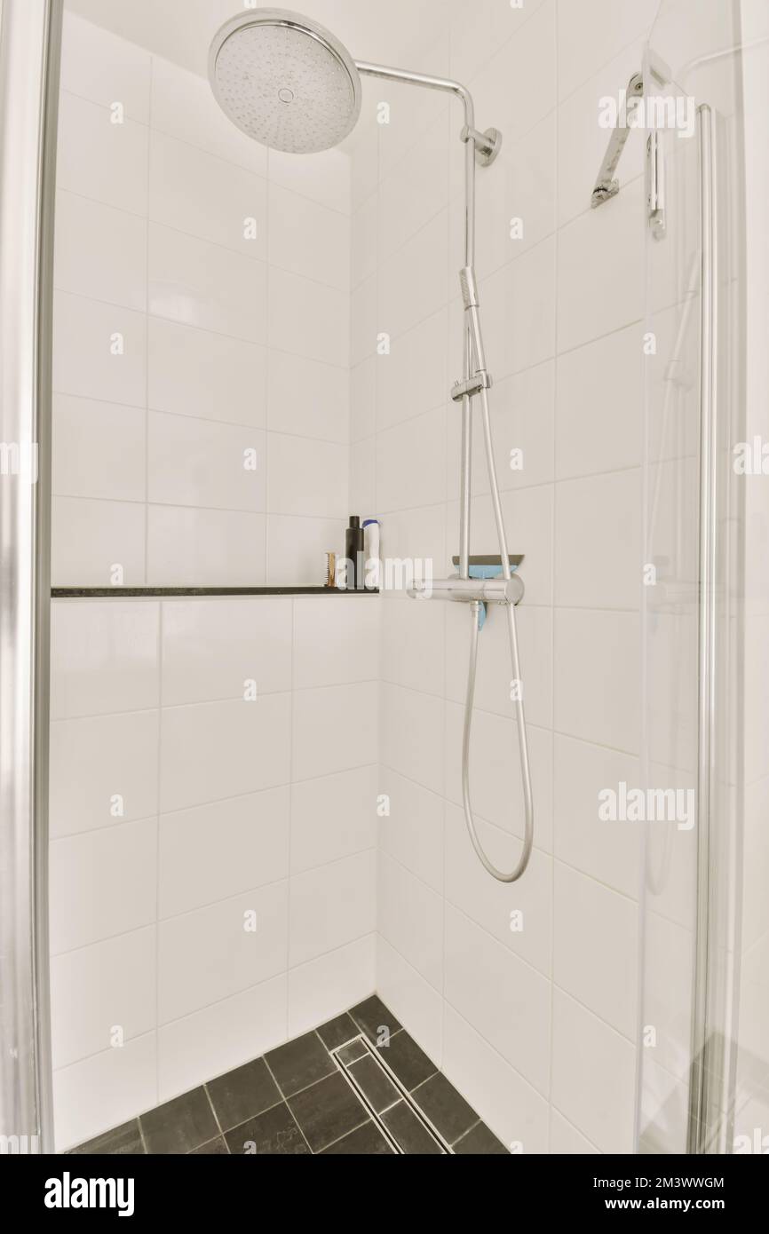 una doccia con piastrelle bianche e nere sul pavimento in un bagno di stile moderno in uno sviluppo di appartamenti a londra Foto Stock