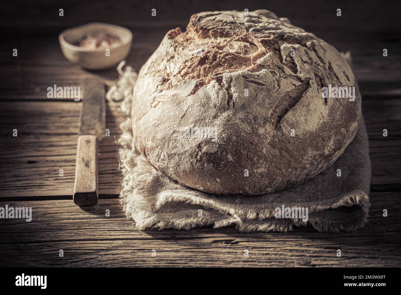 Pagnotta di pane con sale su tela di lino e tavolo di legno Foto Stock